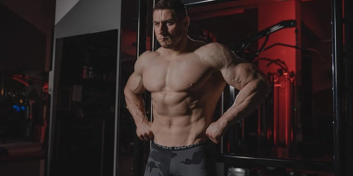 Shirtless bodybuilder flexing muscles under dramatic gym lighting. Fitness and strength.